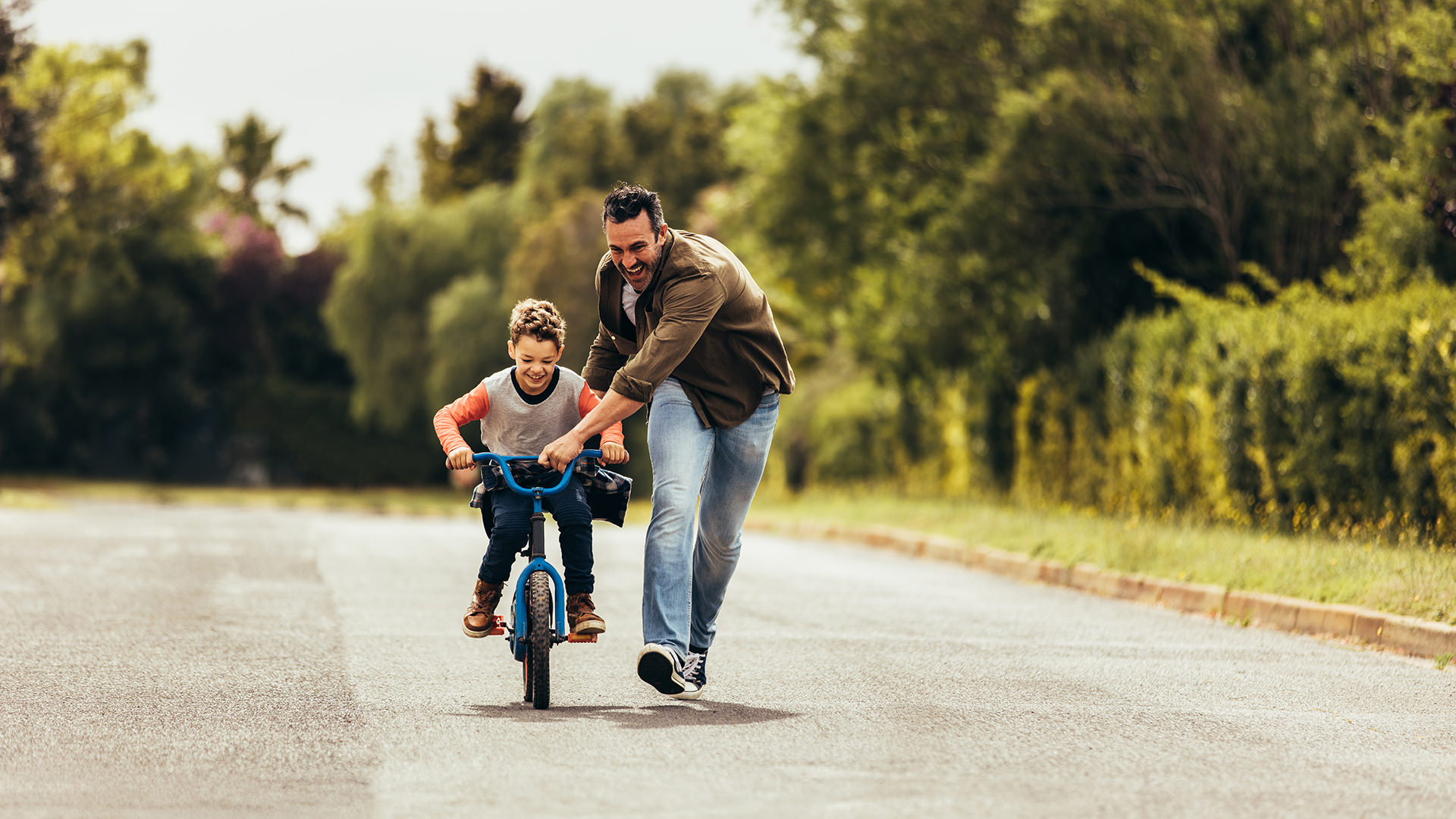 Father teaching his son to ride a bicycle Father helping son learn how to ride a bike