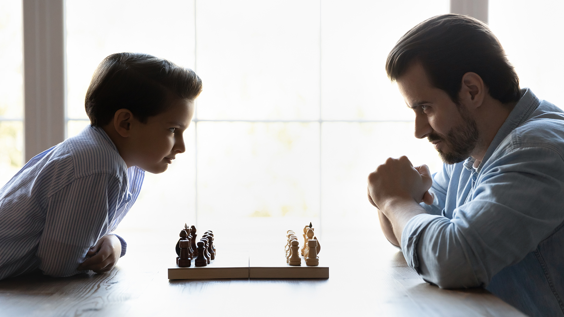 Young Caucasian dad and small son ready for chess match Boy playing chess with a man