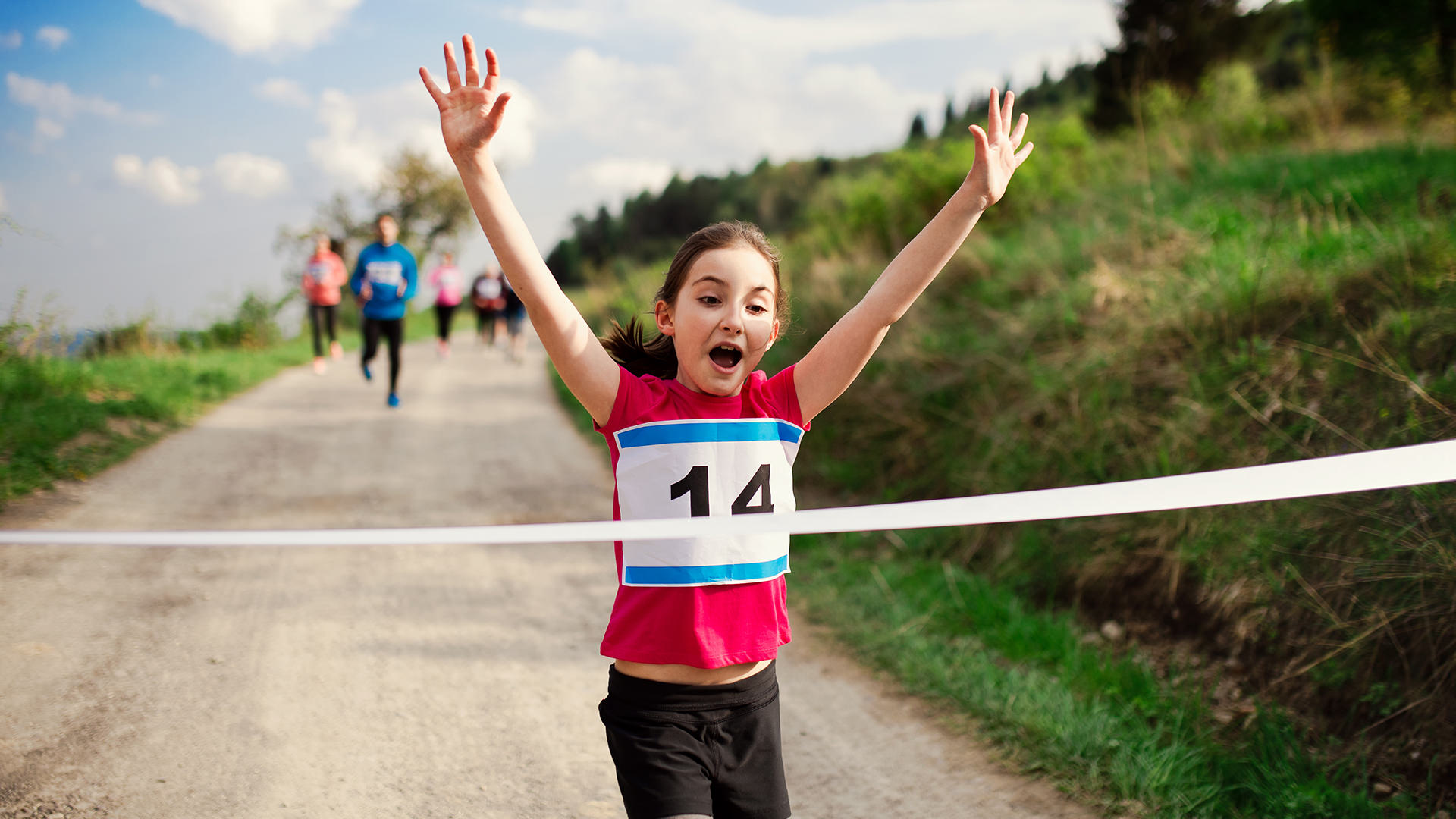 Small girl runner crossing finish line in a race competition in nature. child winning running race